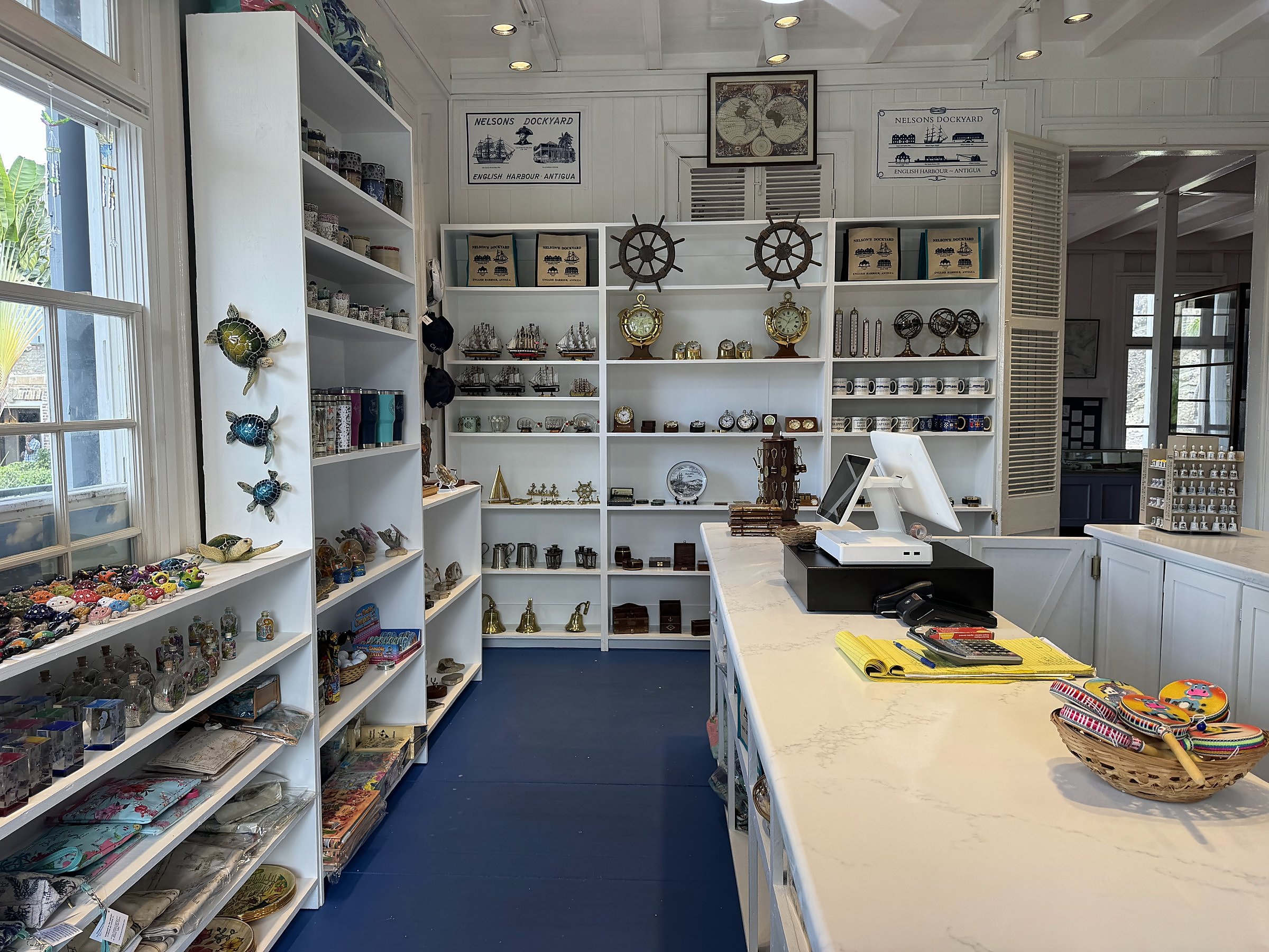 Nelson's Dockyard Gift Shop — register side of the counter, with maritime instruments and mementoes displayed on rebuilt wall shelving