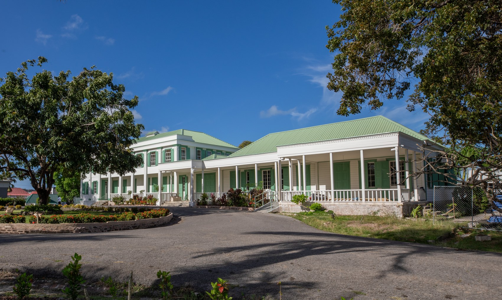 Government House — approach view showing the verandah wing, restored green roof, and entrance gardens