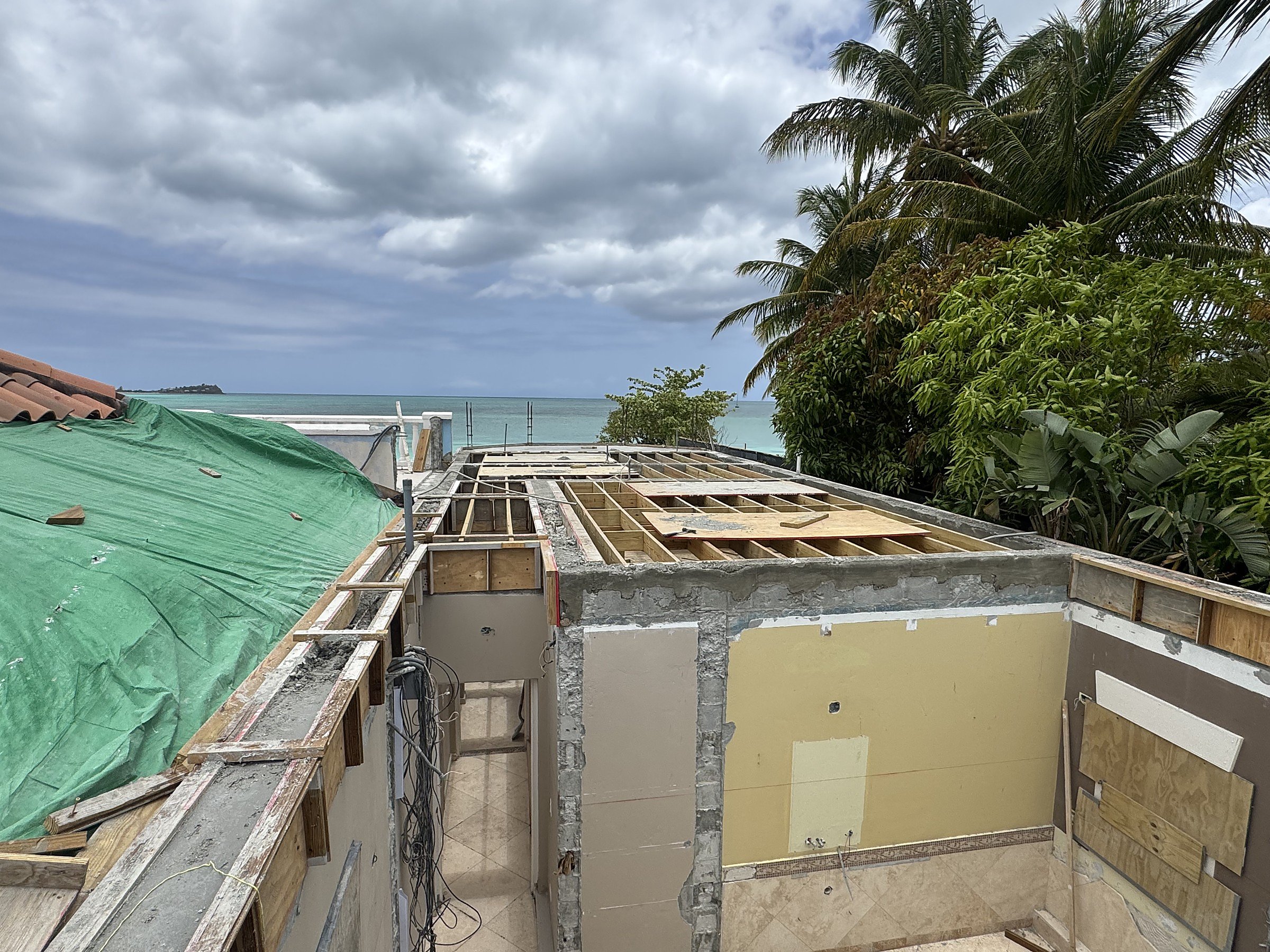 Jolly Harbour Residence — existing roof opened up, new second-level shell under construction, ocean view beyond