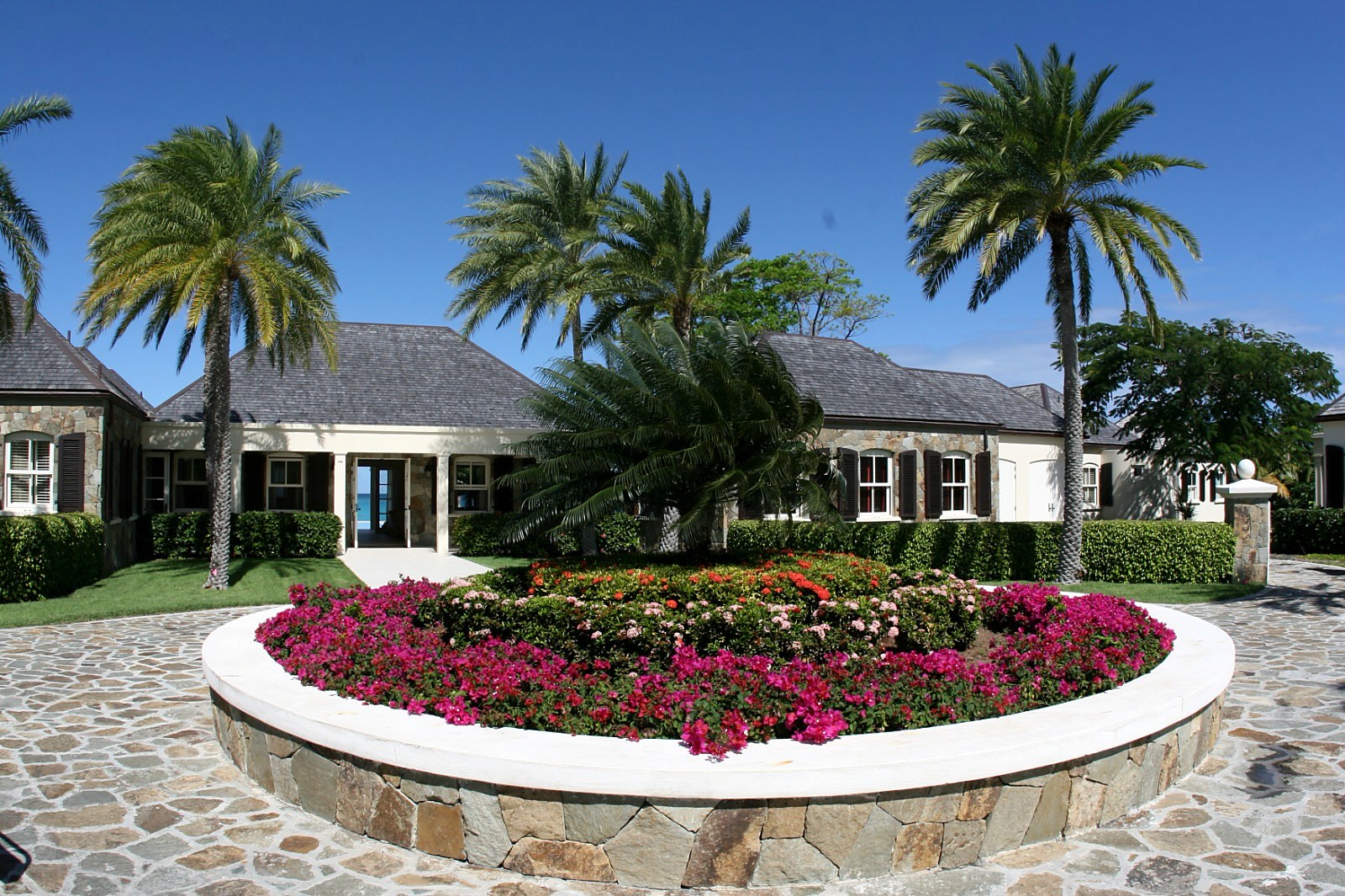 A Jumby Bay residence — stone-walled house with shake-tile roof, bougainvillea garden and formal arrival court. Built by Elderfield Gibbs Smith, Master Builder.