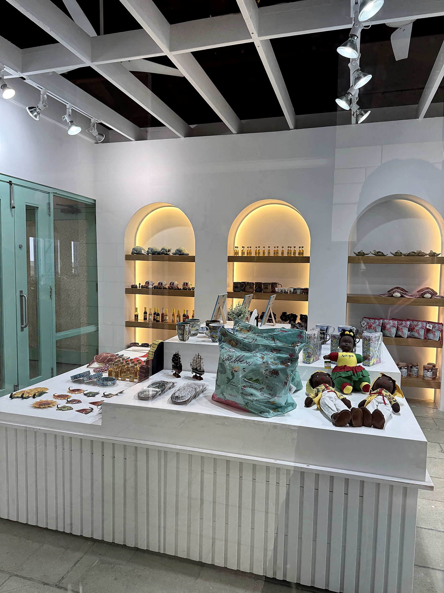 Interpretation Centre Gift Shop at Dow's Hill — full interior view showing illuminated arched niches, exposed structural ceiling joists, restored historic doorway, and central millwork display unit