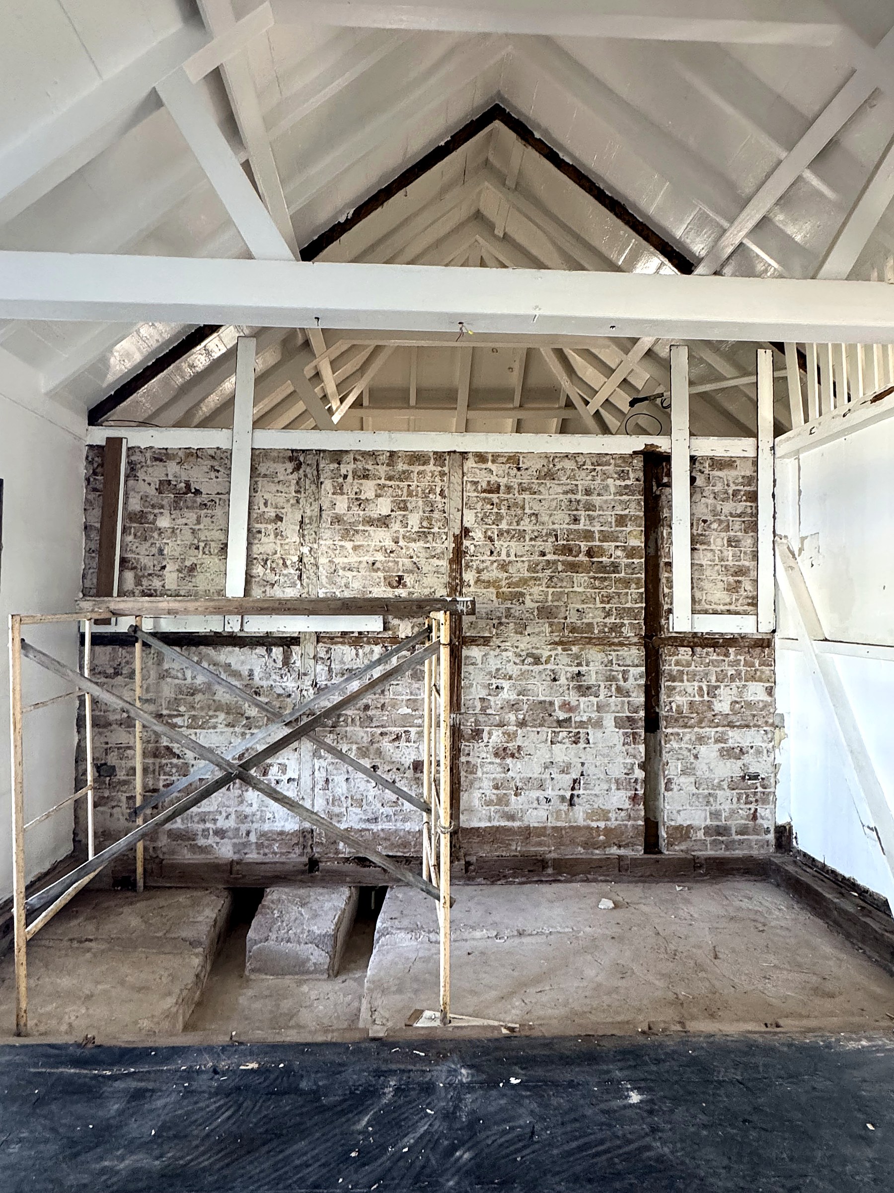 Officers' Quarters interior — exposed gable roof structure and original brick wall during restoration